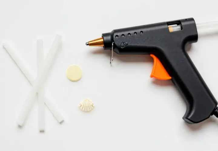 Pistolet do kleju na gorąco, kilka pałeczek kleju, muszelka i żółty krążek. Czy klej na gorąco przewodzi prąd?