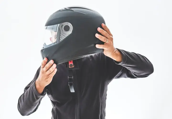 Persona indossa un casco nero, mostrando le sue parti. Le mani regolano il cinturino e la visiera.