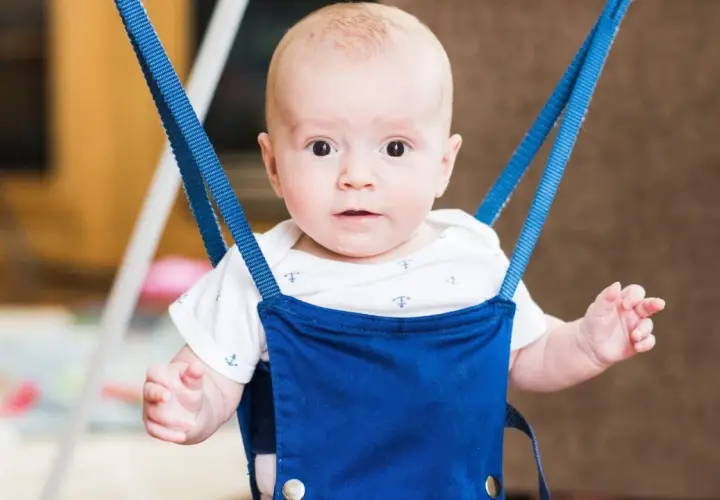 Uśmiechnięty bobas w niebieskim skoczku dla dzieci, wspierający rozwój ruchowy i fizjoterapię.