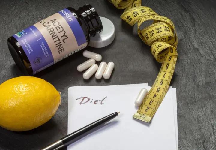 Flasche Acetyl-L-Carnitin, Maßband, Zitrone und Notiz "Diet". Die L-Carnitin Wirkung wird hier für eine Diät dargestellt.