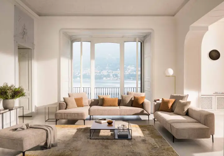 Salon lumineux avec canapé modulable, pouf et tapis doux pour une deco appartement cocooning parfaite. Vue sur lac et ville.