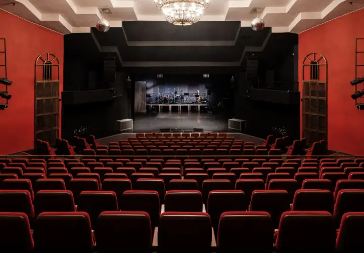 Widownia teatru na Targówku, z rzędami czerwonych foteli i sceną gotową na występ.