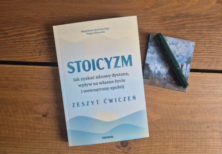 Książki o stoicyzmie na drewnianym stole. Zeszyt ćwiczeń "Stoicyzm" zachęca do zdrowego dystansu i wewnętrznego spokoju.