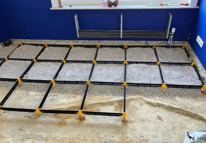 Vorbereitung für **OSB-Platten verlegen**: Ein Boden wird mit Schotter gefüllt und mit einem schwarzen Gitter und gelben Clips für den Trockenestrich vorbereitet.