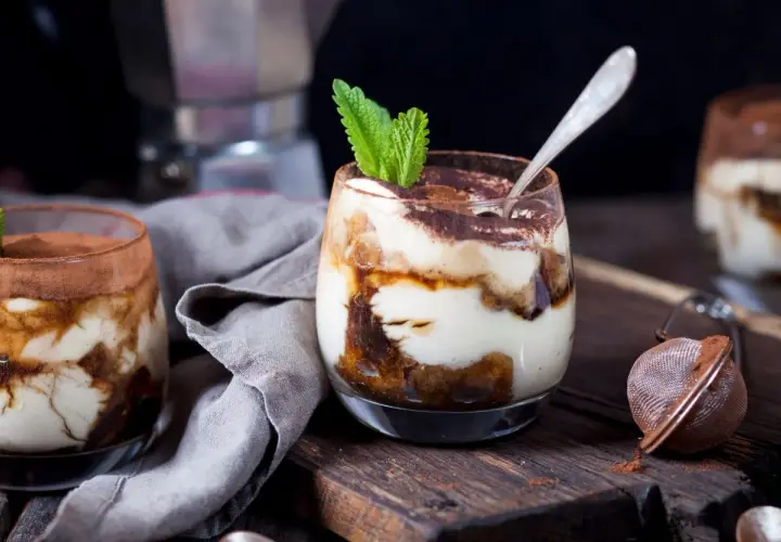 Pyszne tiramisu z mascarpone w pucharkach, udekorowane miętą i kakao. Idealny sprawdzony przepis na deser.