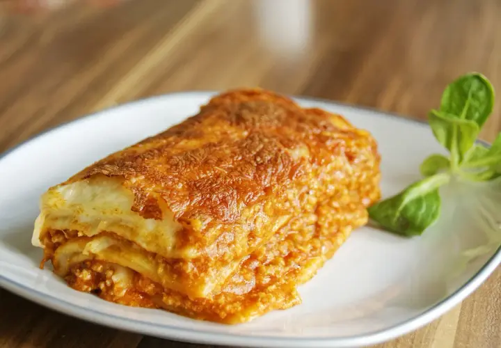 Pyszna, zapieczona lasagne z mięsem mielonym na talerzu. Idealna na prosty obiad.