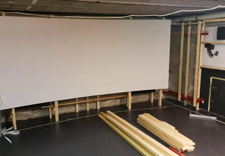 Große, weiße Leinwand für ein Heimkino, gestützt von Holzrahmen. Material für den **Beamer Leinwand selber bauen** liegt bereit.