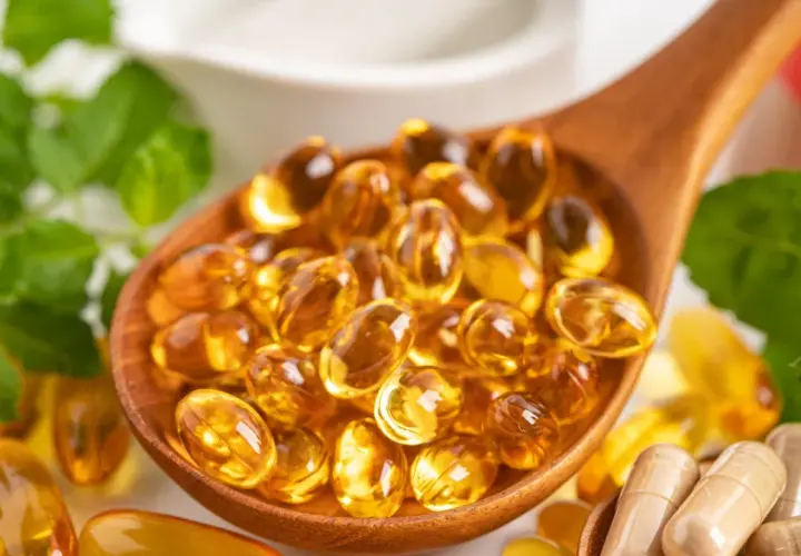 Łyżka pełna kapsułek z omega 3. Kwasy te wspierają serce, mózg i wzrok.