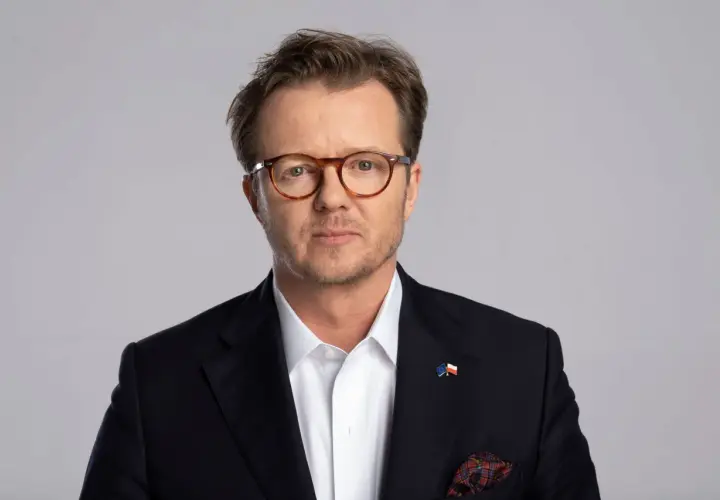 Michał Wawrykiewicz, prawnik i działacz społeczny, w garniturze z flagami UE i Polski. Jego życiorys to historia walki o prawa obywatelskie.