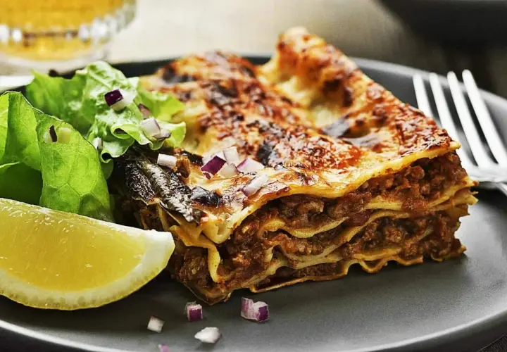En saftig bit lasagne med köttfärs och ost, serverad med en fräsch sallad och citronklyfta. Perfekt för lasagnens dag!