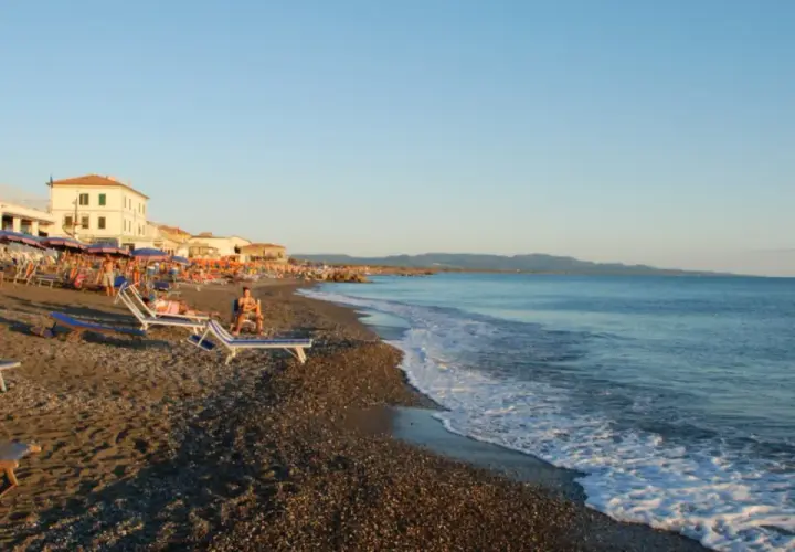 Plage de Cecina, Italie. Chaises longues et parasols sur le sable, mer calme sous un ciel bleu.