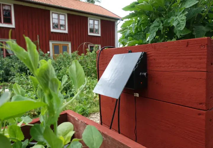 En solcellsdriven bevattning sköter om växterna vid ett rött hus.