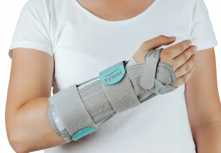 Szara orteza na nadgarstek, która zapewnia stabilizację, lepsza niż gips.
