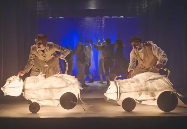 Aktorzy Teatru Lalki i Aktora Wałbrzych prowadzą świetliste, papierowe zwierzęta na scenie.