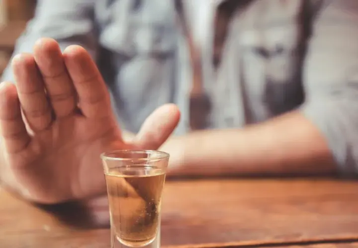 Dłoń odpycha kieliszek z alkoholem. Decyzja o abstynencji, jak naltex, jest ważna.