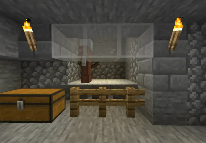 W klatce z Minecrafta stoi villager, gotowy na komendę na zabicie mobów. Obok skrzynia i pochodnie.