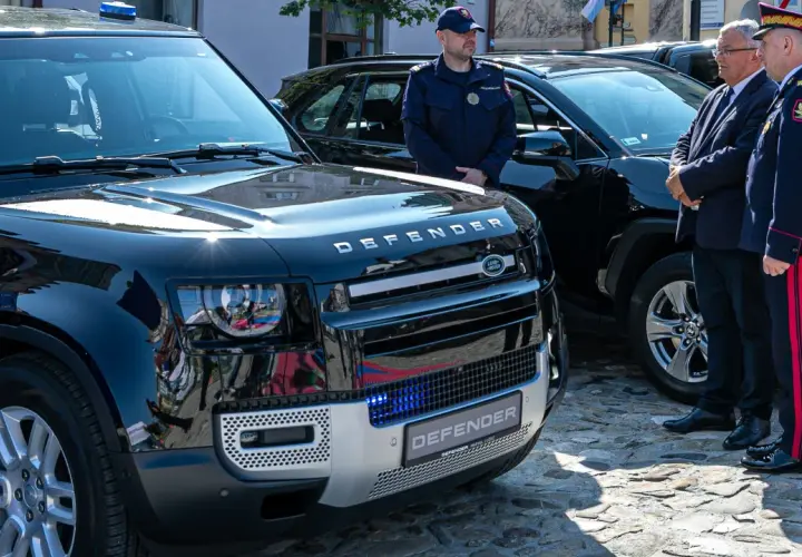 Nowy Land Rover Defender, mały pojazd szynowy, lśni w słońcu. Obok stoją funkcjonariusze w mundurach.