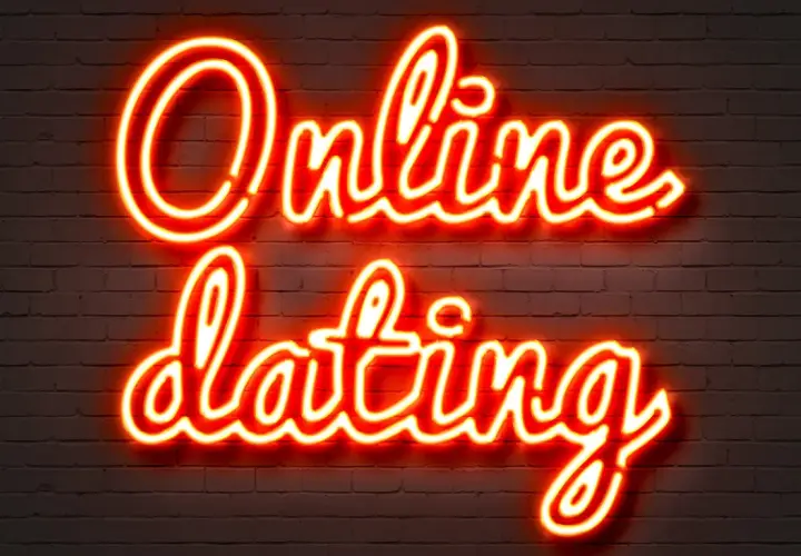 Neonowy napis "Online dating" na ceglanej ścianie. Szukasz odpowiedzi, gdzie poznać dziewczynę w sieci?