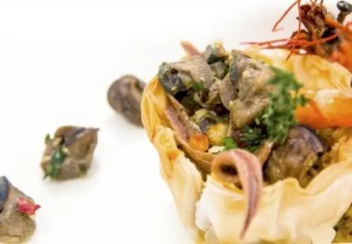 Wykwintne danie ze ślimaków w cieście filo, idealne na ślimak catering Kraków. Krewetka i zioła dopełniają kompozycję.