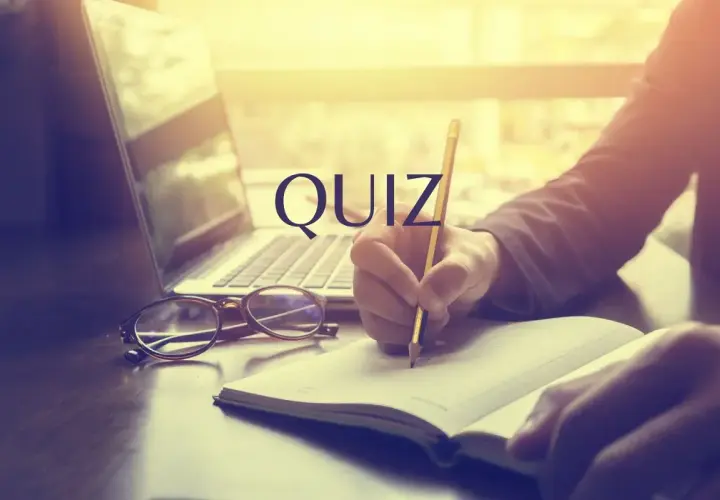 Quiz o prawach pracownika. Osoba pisze w notatniku przy laptopie i okularach.