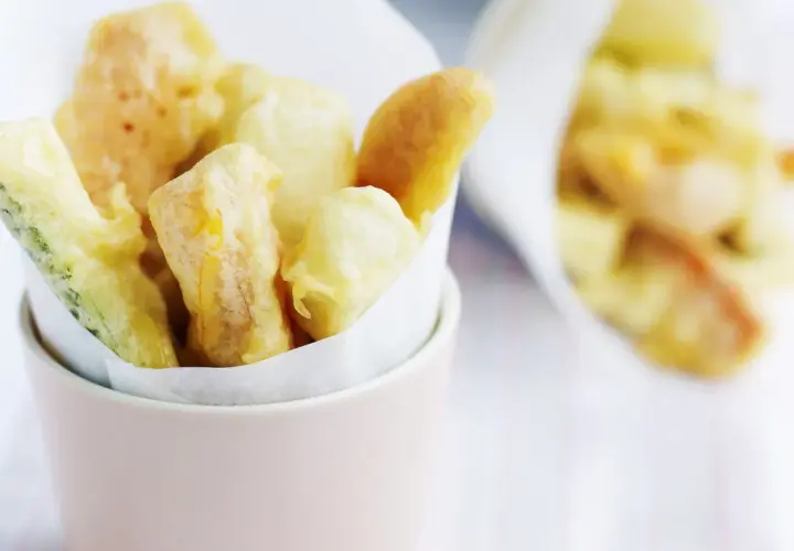 Verdure croccanti immerse in una leggera pastella per verdure fritte, servite in un contenitore rosa.