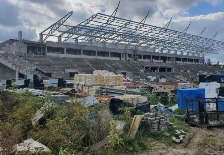 Budowa stadionu RKS Radomiak Radom w toku. Betonowe trybuny i stalowa konstrukcja dachu, wokół materiały budowlane.