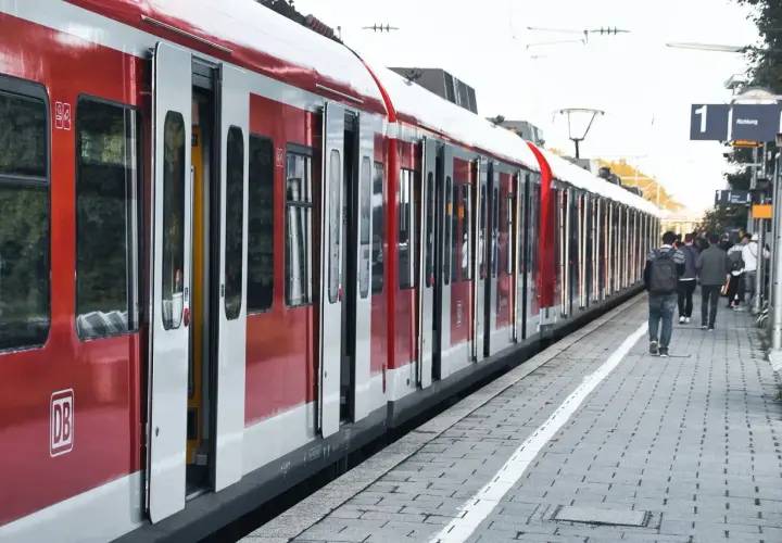 Czerwony pociąg na stacji, ludzie czekają na peronie. Może ktoś właśnie kupił bilet, a teraz zastanawia się nad zwrotem biletu.