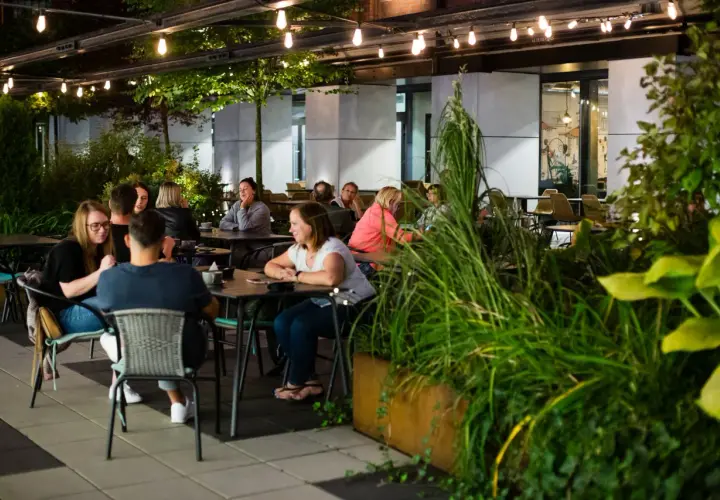 Wieczorny relaks w jednej z nowych restauracji w Łodzi. Ludzie siedzą przy stolikach, delektując się posiłkami i rozmowami.