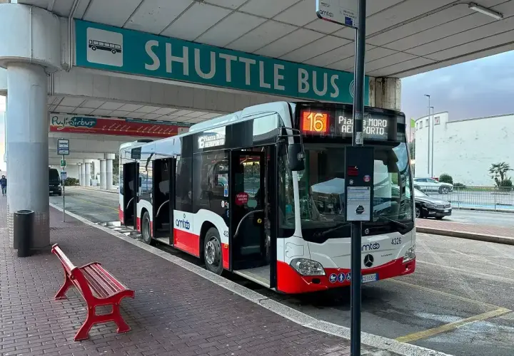 Autobus wahadłowy na lotnisko Bari. Czerwona ławka czeka na pasażerów pod znakiem "SHUTTLE BUS".