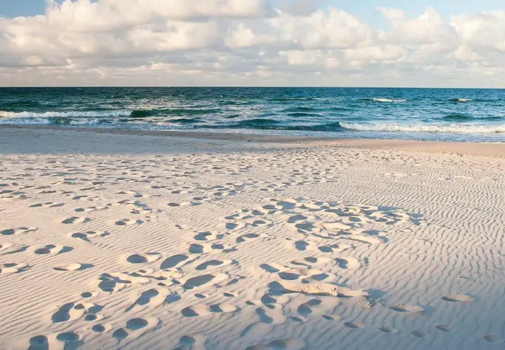 Piasek na plaży, ślady stóp i fale Bałtyku. Idealne miejsce, by pomyśleć, gdzie nad morze.