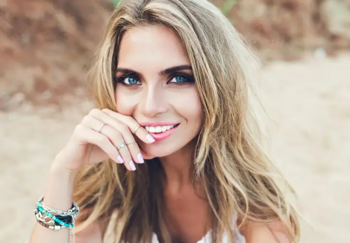 Blondynka o niebieskich oczach, zmysłowo uśmiechnięta. Idealne kolory ubrań dla blondynek o niebieskich oczach podkreślą jej urodę.