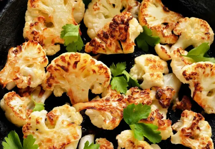 Chou-fleur rôti au four, doré et caramélisé, garni de persil frais dans une poêle en fonte. Un délice croustillant.