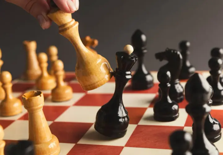Ręka przesuwa jasnego króla, by zbić czarnego króla. Strategia jak sprzedać akcje.