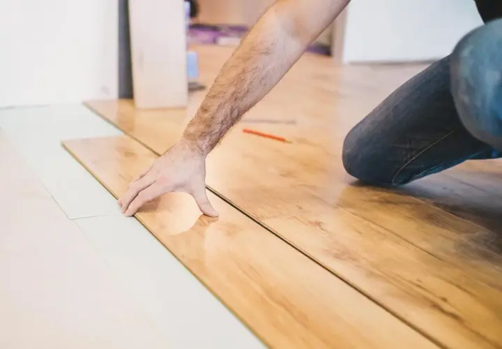 Installazione di parquet laminato: un uomo posa le tavole, mostrando come tagliare spc.