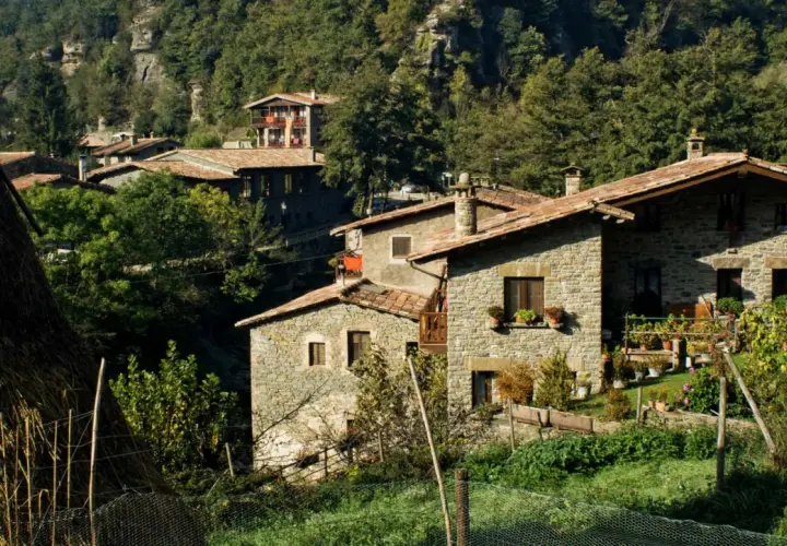 Casas de piedra con tejados rojos en un entorno boscoso, ideal para el turismo rural sostenible.