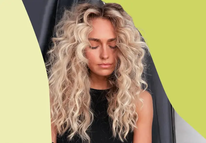 Mujer con cabello rubio, rizado y esponjoso, con los ojos cerrados y un ligero bronceado.