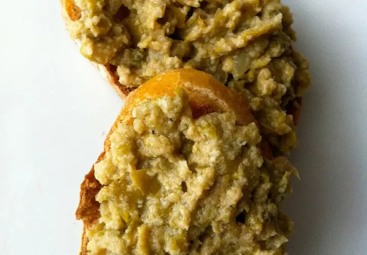 Deux tranches de pain garnies d'une généreuse portion de tapenade verte, prêtes à être dégustées.