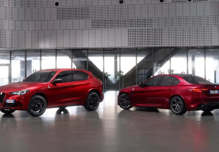 Dwa czerwone Alfa Romeo, SUV Stelvio i sedan Giulia Quadrifoglio, stoją obok siebie w nowoczesnym wnętrzu.