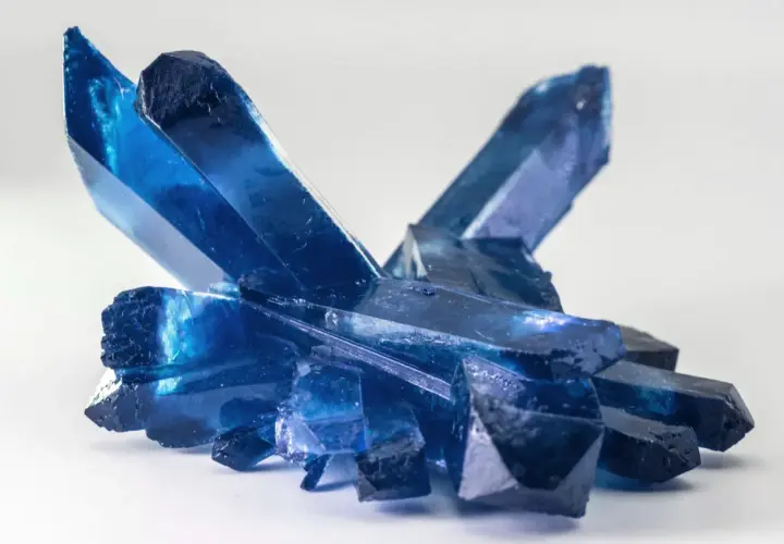 Ein Cluster tiefblauer Kristalle, die an gefrorene Eisspitzen erinnern. Die Bedeutung eines blauen Steins wird oft mit Ruhe und Klarheit assoziiert.