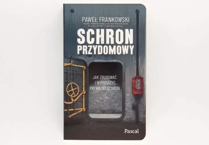 Okładka książki "Schron przydomowy" Pawła Frankowskiego. Przedstawia wejście do schronu z żółtą kierownicą i czerwoną skrzynką elektryczną.
