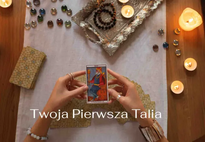 Ręce trzymają kartę Tarota "Cesarz". Wokół świece, kamienie i talia kart. Idealne na początek przygody z wróżeniem, jakie karty tarota dla początkujących.