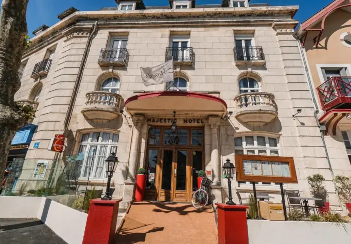 Façade de l'hôtel Majestic à Châtelaillon-Plage avec son entrée principale en bois et un drapeau blanc.
