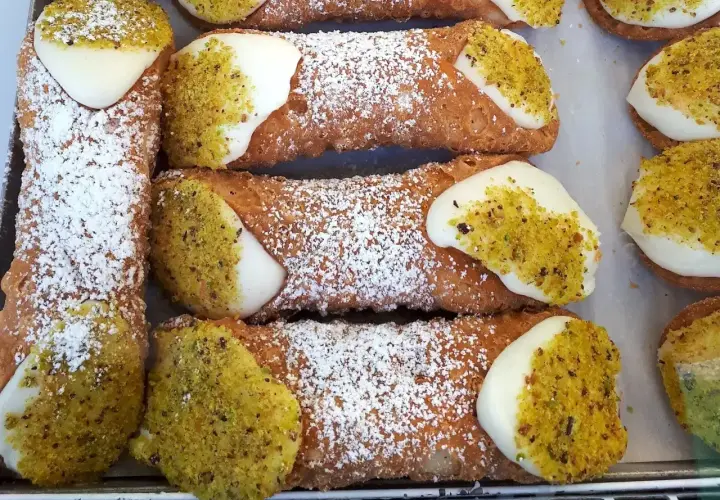 Chrupiące rurki z kremem i pistacjami, posypane cukrem pudrem. Idealne na deser, jak z najlepszego cannoli przepisu.