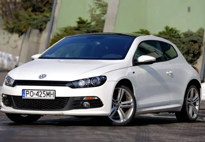 Biały Volkswagen Scirocco z czarnym dachem, zaparkowany na zewnątrz.