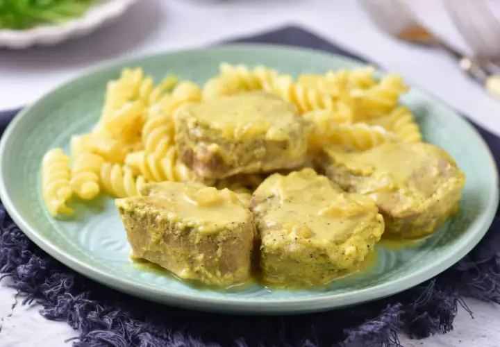 Soczyste polędwiczki w sosie musztardowym podane z makaronem fusilli na zielonym talerzu.