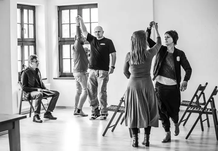 Grupa ludzi ćwiczy w sali, przygotowując się do spektaklu. To scena z życia **teatru polskiego w podziemiu**, gdzie pasja tworzy sztukę mimo trudności.
