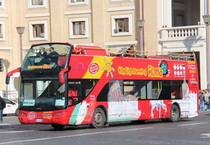 Un bus rouge à deux étages, un bus touristique "City Sightseeing Roma", circule dans la ville.
