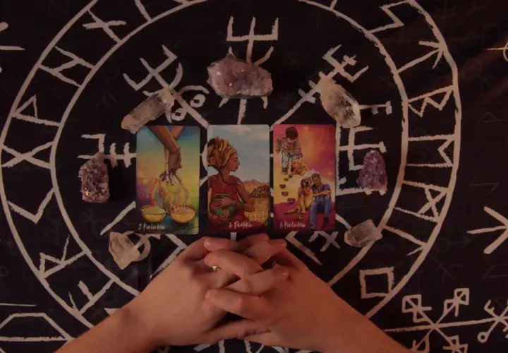 Horoskop miesięczny Lew Tarot: karty i kryształy na tle runicznym.