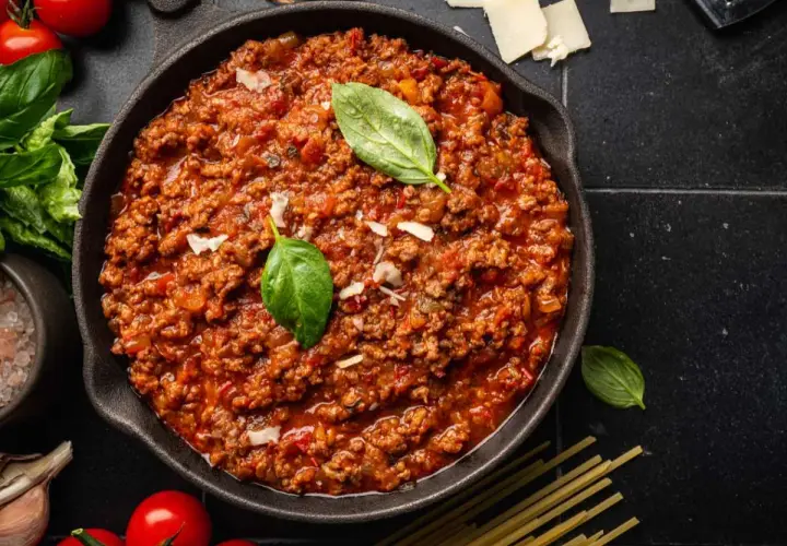 Un delicioso plato de spaghetti bolognese original, con carne picada, tomate y albahaca fresca.