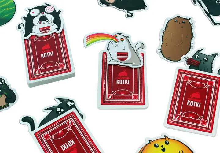 Karty z gry "Eksplodujące Kotki: Imprezka" przedstawiają szalone koty, jeden z tęczą z pyska, inny z dynamitem.